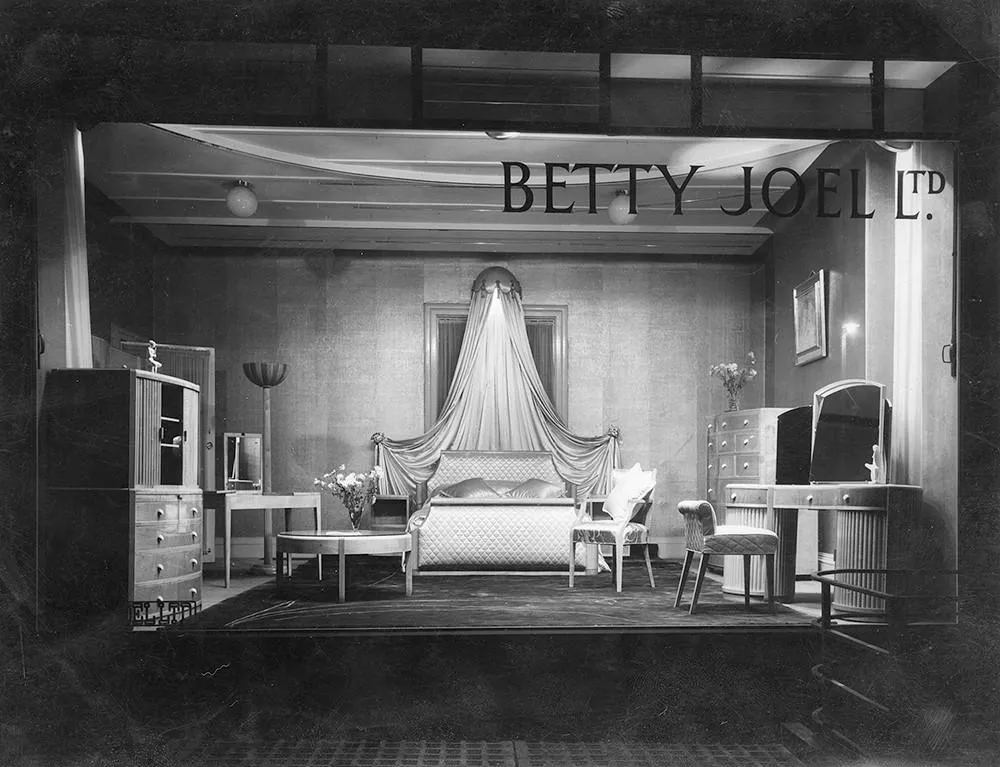 Showroom window showing a bed and cabinets with Betty Joel Ltd. on the window