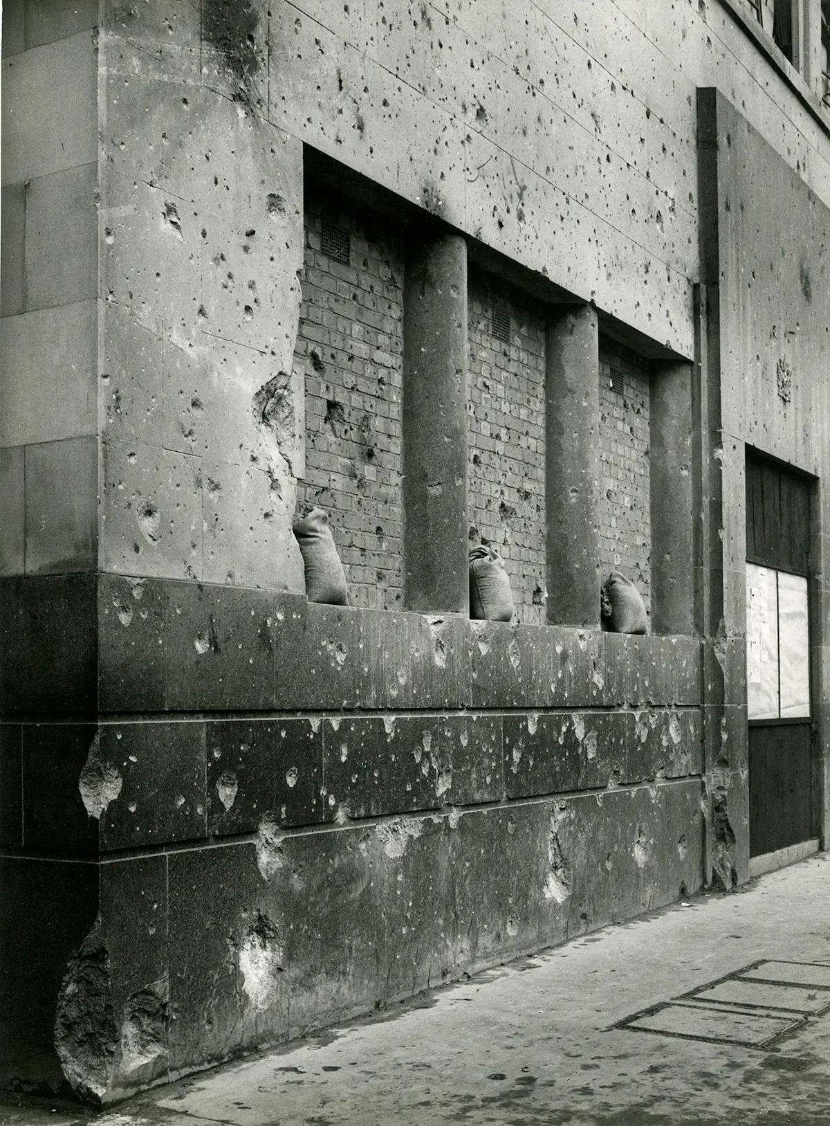 A wall covered with bullet holes and sandbags