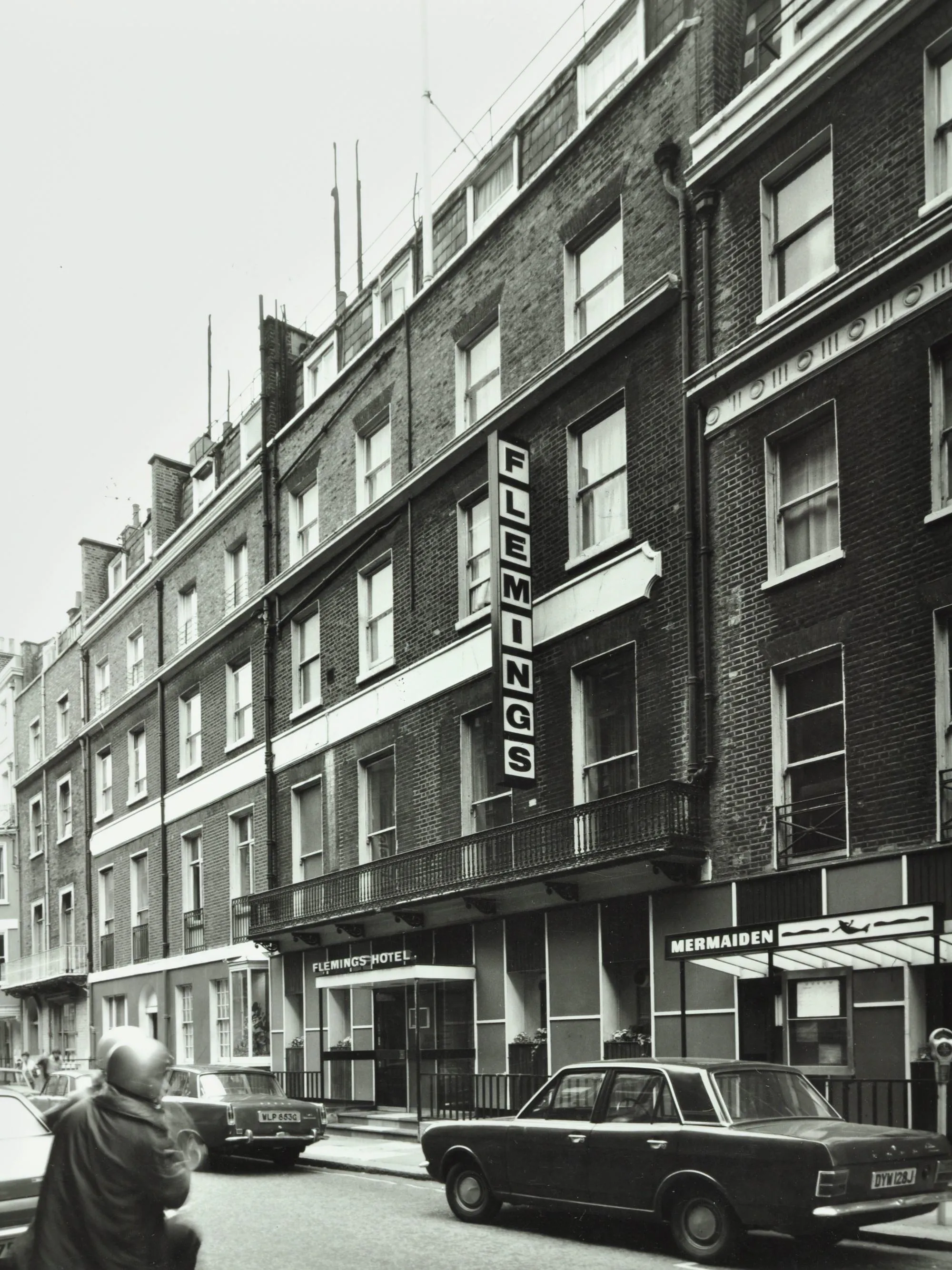 a row of terraced buildings with a vertical sign indicating Flemings hotel