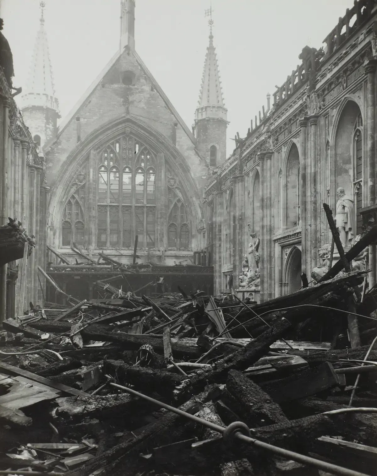 Burnt timbers from a destroyed roof in front of surviving walls and statues
